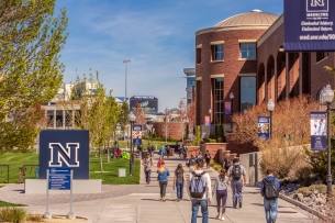 The University of Nevada at Reno campus with buildings on the right and a blue sign on the left with a capital “N” in the center