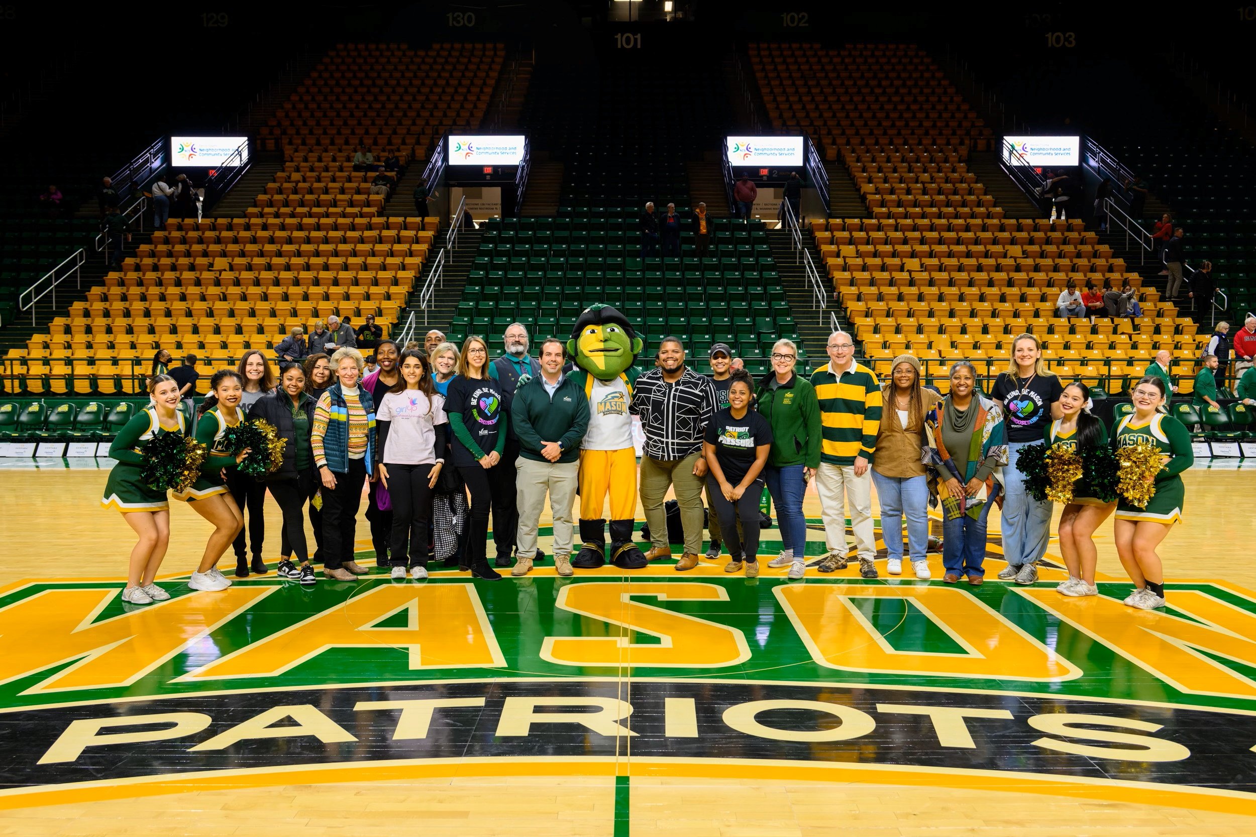 A group of George Mason University kindness ambassadors, students and cheerleaders pose with the mascot for a photo in the basketball arena