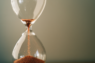 A photo of an hourglass, with the dropping of sand signaling the passage of time.