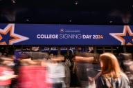 People moving in front of a sign that says College Signing Day 