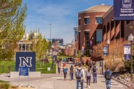 The University of Nevada at Reno campus with buildings on the right and a blue sign on the left with a capital “N” in the center
