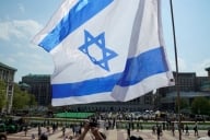 An Israeli flag waves in the foreground in a photo of Columbia University’s campus.
