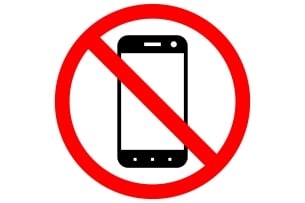 A sign prohibiting smartphone usage, featuring a black-and-white drawing of a smartphone inside a red circle with a diagonal slash through it.
