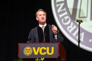 A photograph of Virginia governor Glenn Youngkin speaking behind a lectern bearing Virginia Commonwealth University’s logo and the letters “VCU.”