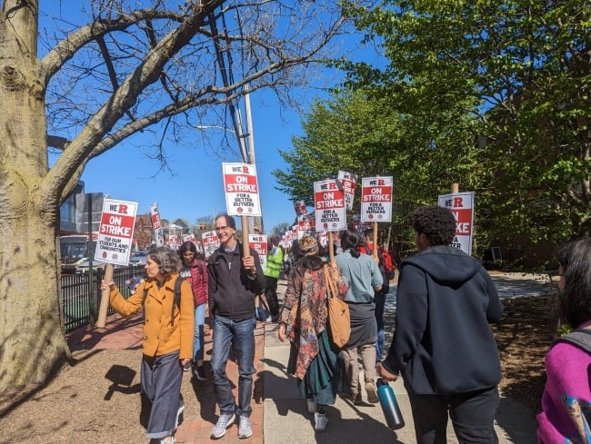 Rutgers University community members holding signs and striking. 