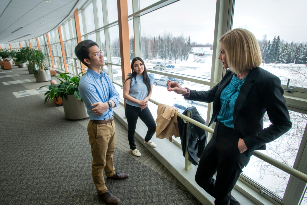 Melanie Hulbert talks with two students in a hallway at the University of Alaska at Anchorage campus.