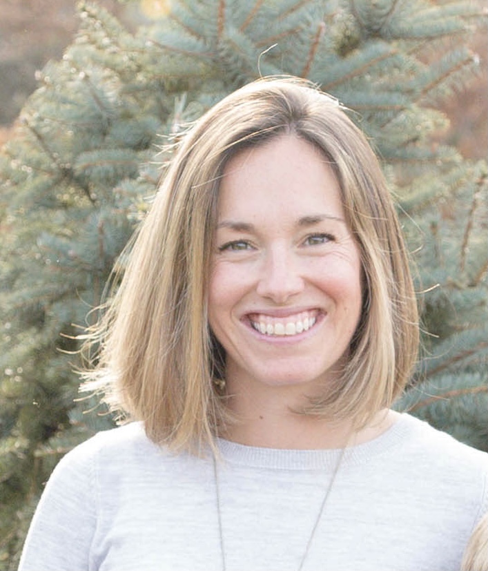 Sarah Ball, a light-skinned woman with blond hair, smiles for a headshot photo.