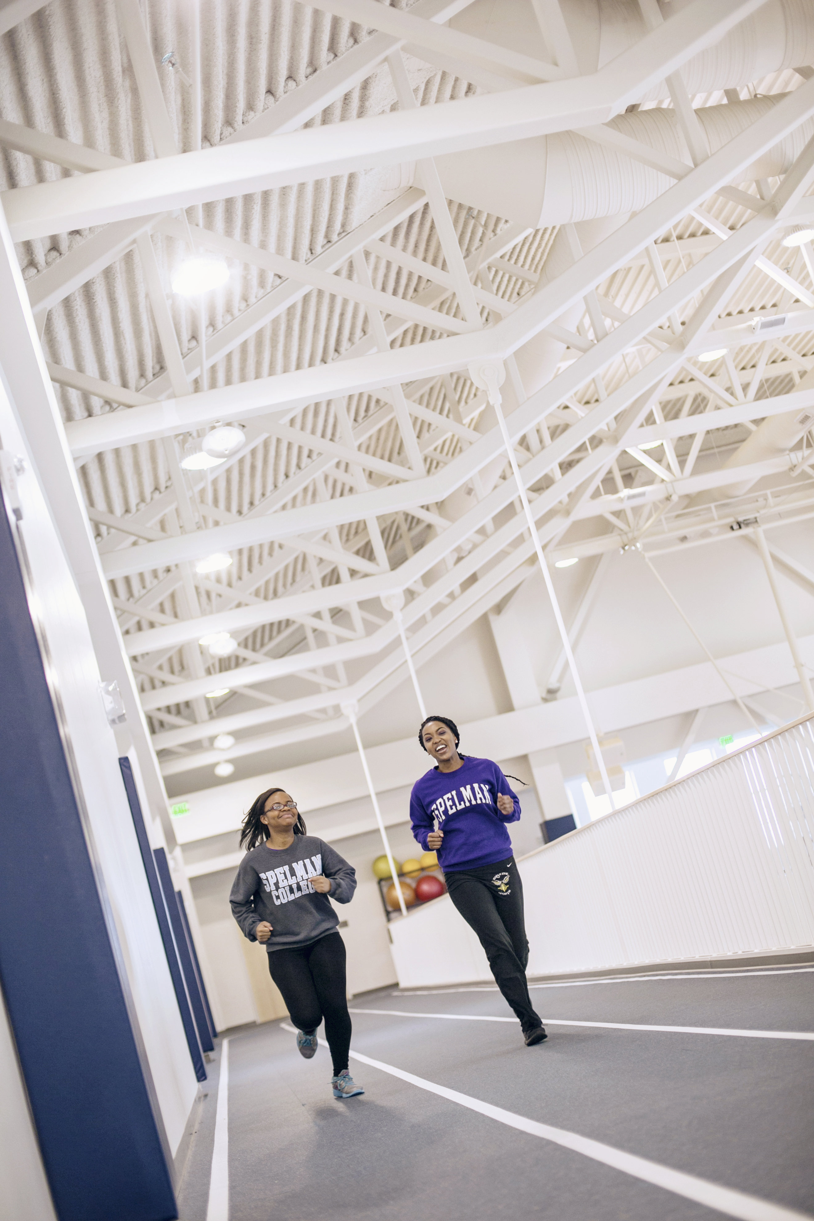Two students at Spelman University run on an indoor track.