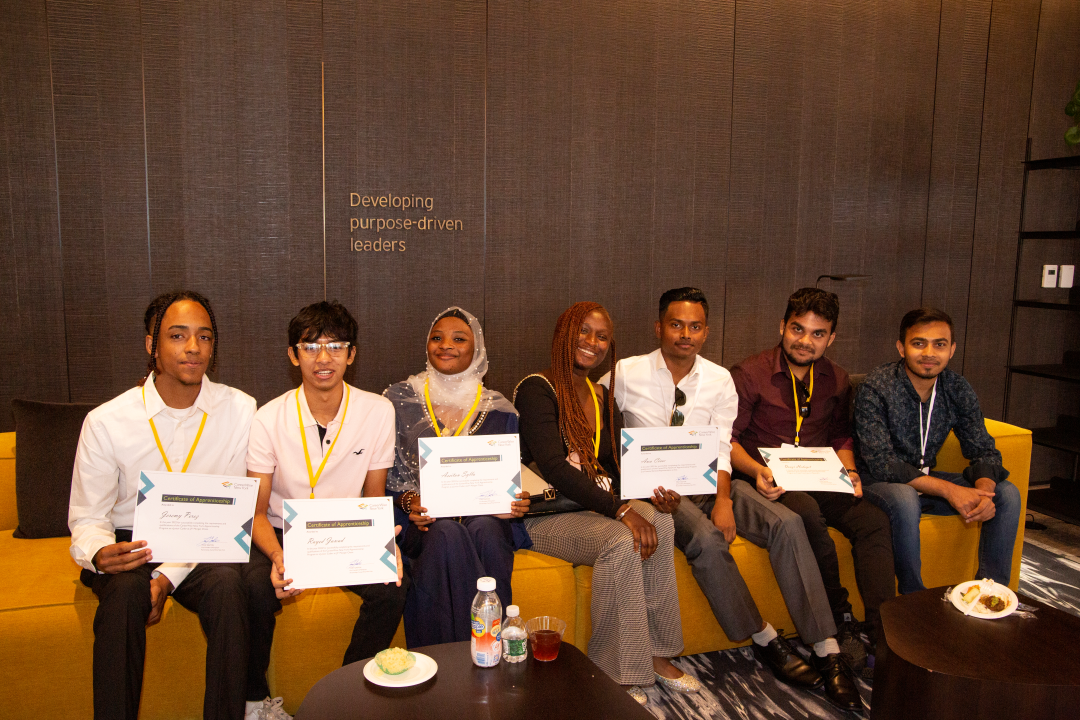 Seven CUNY apprentices sit on a yellow couch holding certificates. 