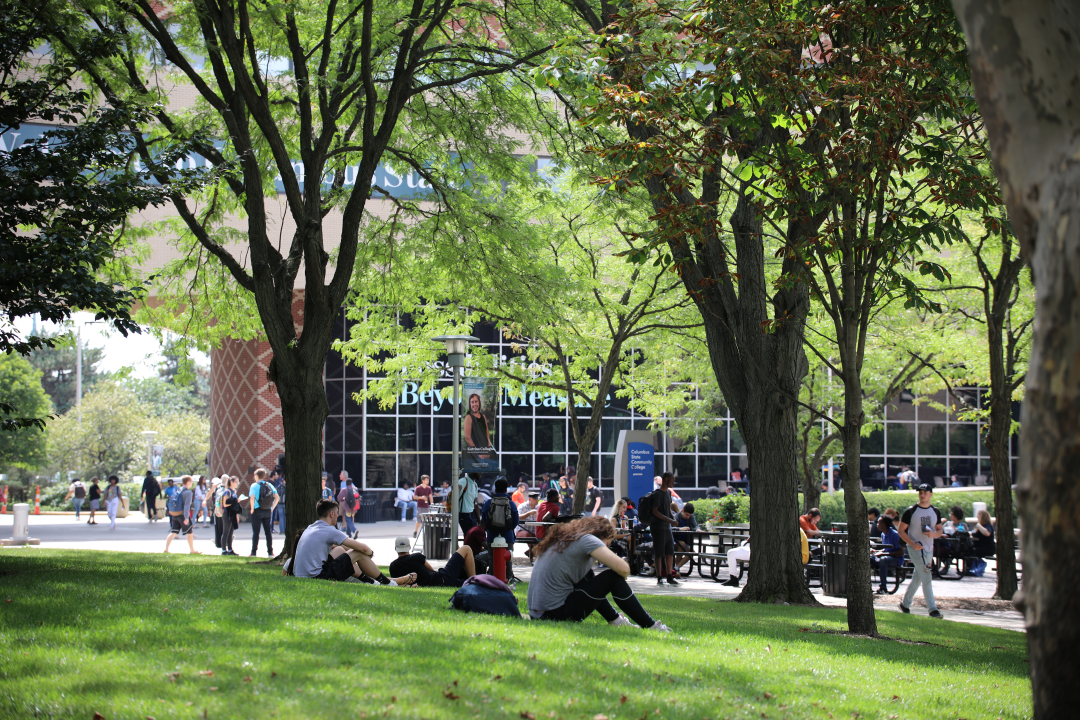 Students sit on the grass on Columbus State Community College's campus.