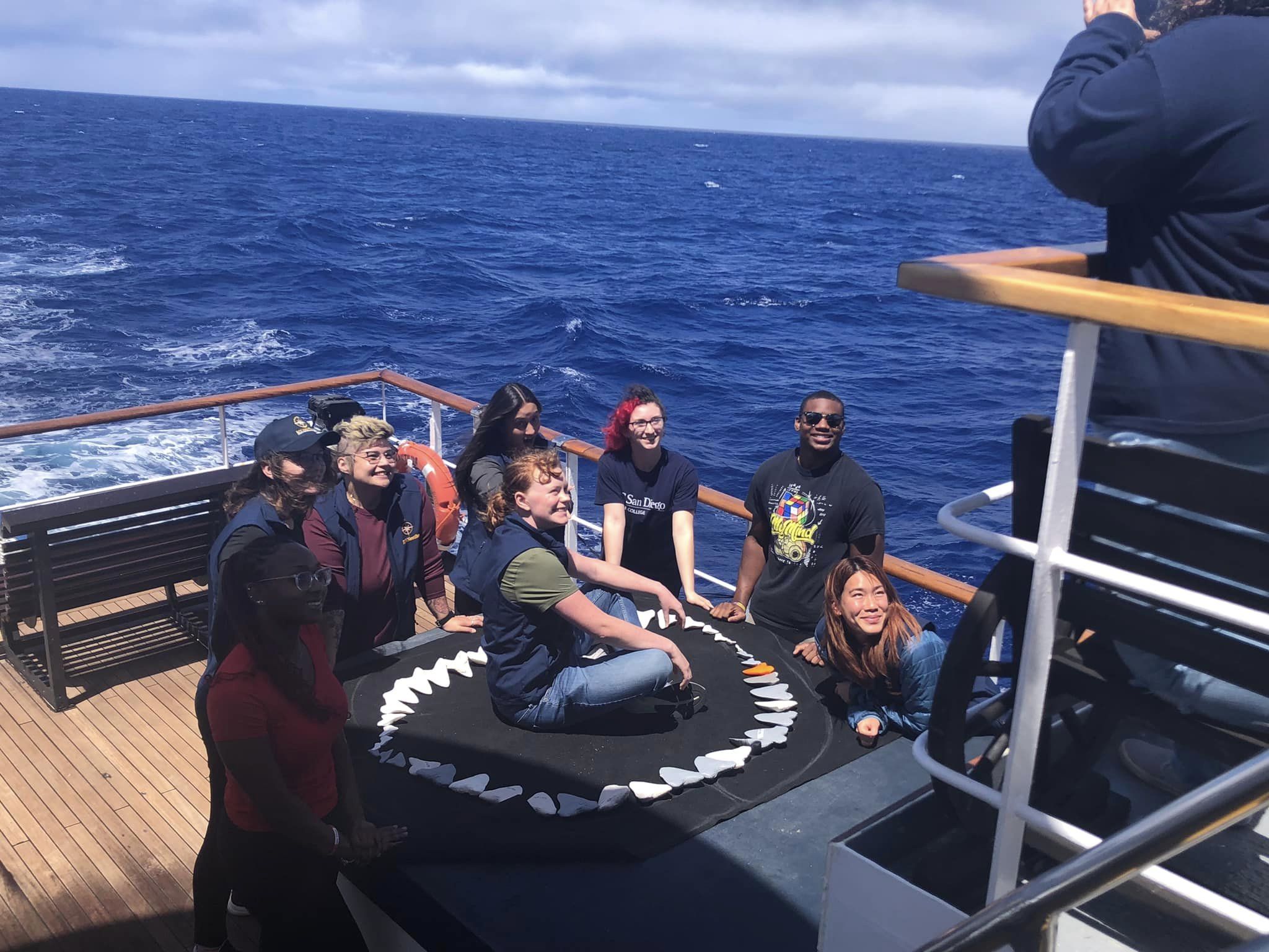 Students pose with a model Megalodon jaw on the E/V Nautilus