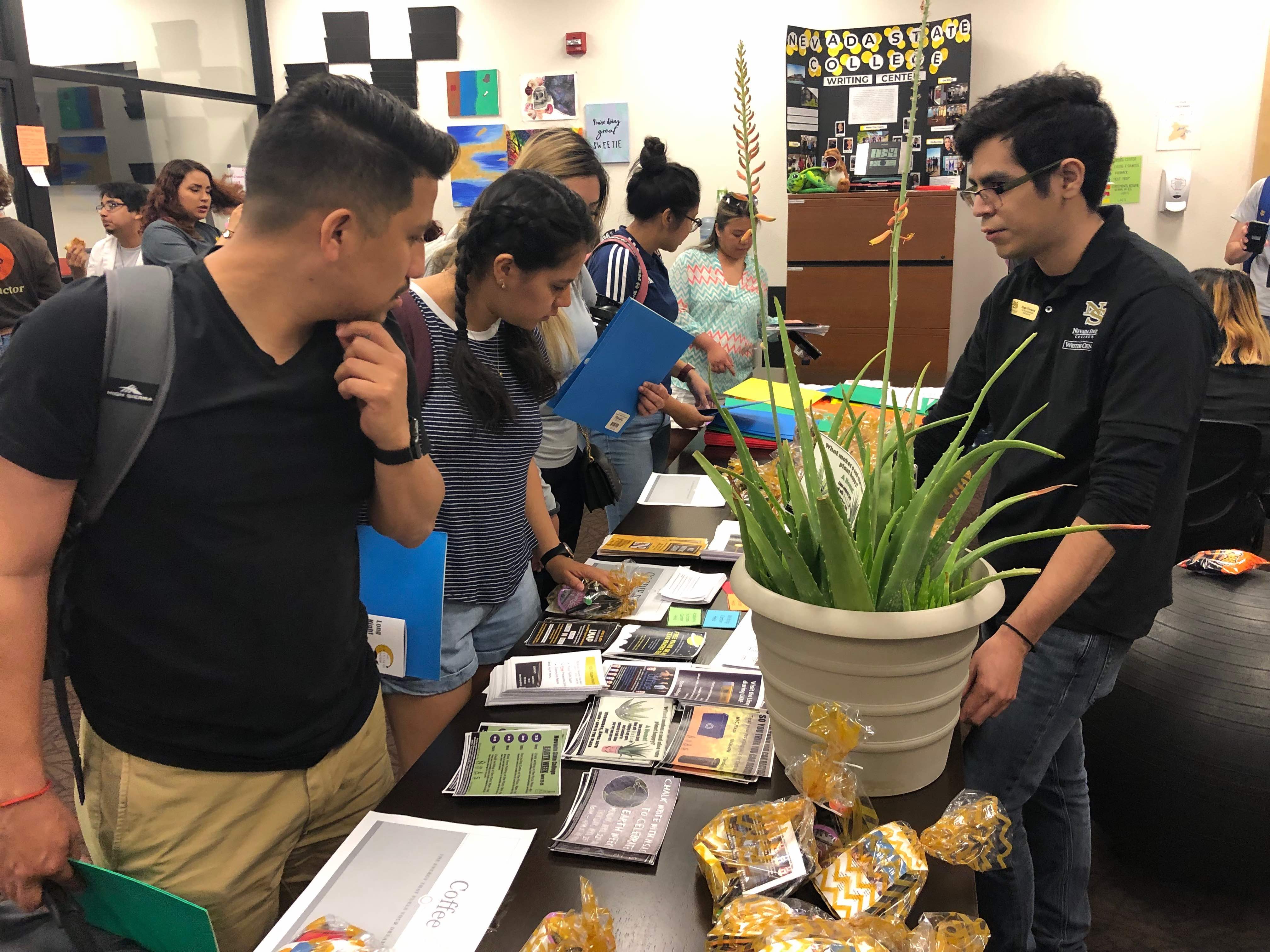 A line of students look at a table full of leaflets inside the library at Nevada State College as part of its long Long Night Against Procrastination.