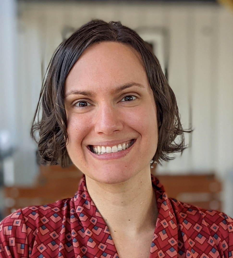 Headshot of Lauren Hensley, a light-skinned woman with short dark hair wearing a red patterned blouse