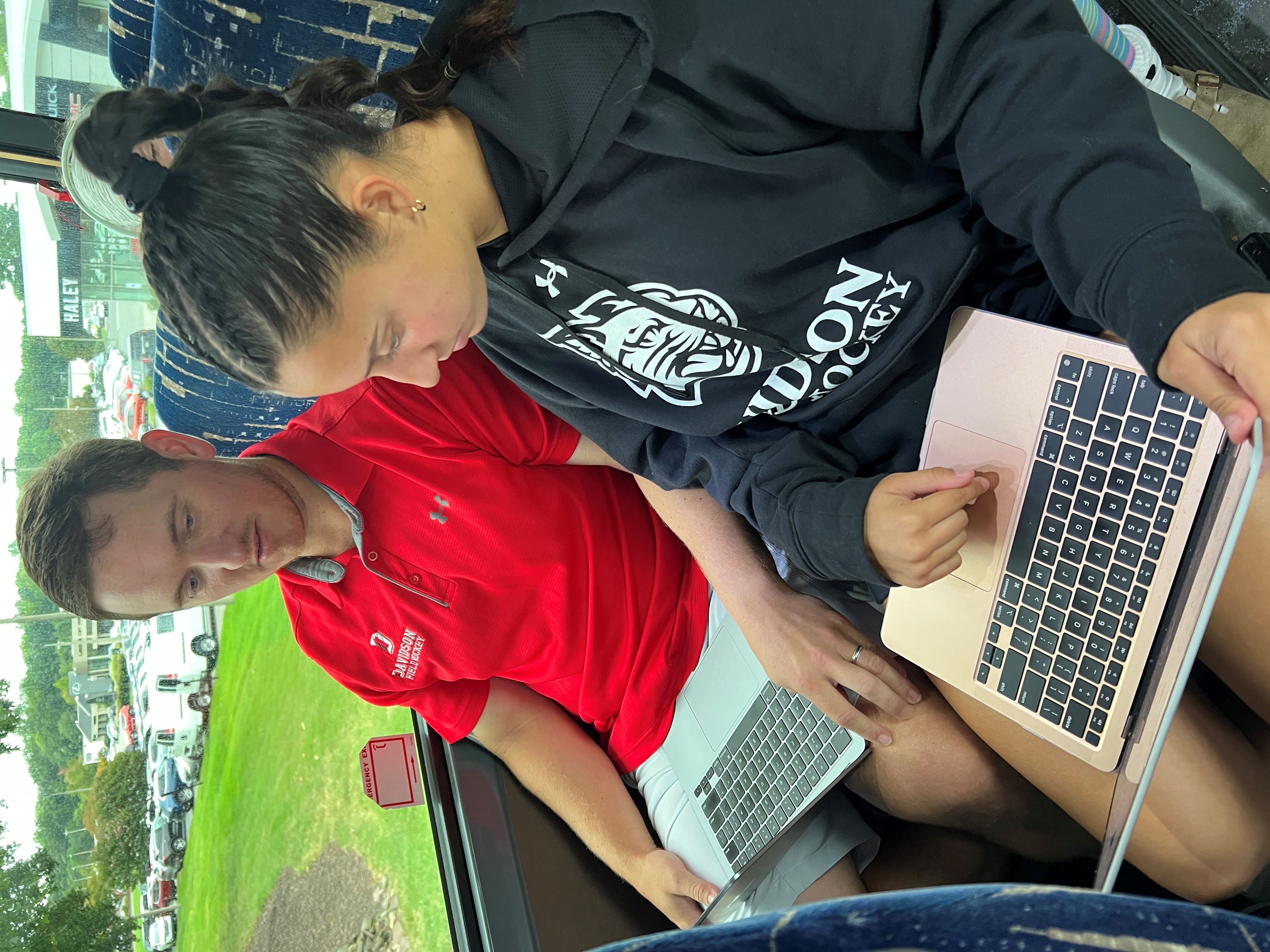 Josh King works with Celie Constantine, a sophomore on Davidson's field hockey team, on a bus ride. 