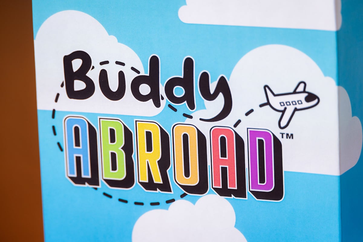 The logo of DePaul University’s board game, Buddy Abroad, features a cartoon airplane and a cloud background