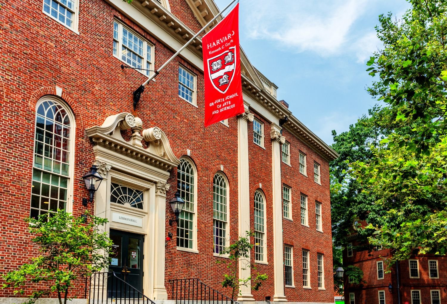 A flag with the Harvard University logo hangs above the entrance of Harvard's Lehman Hall.