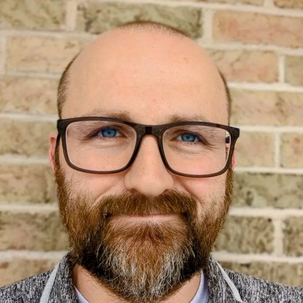Lance Eaton, a light-skinned man with glasses and a reddish beard that is just lightly gray at his chin.
