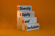 A stack of four blocks, each bearing one of the words "Diversity," Equity" "and" "Inclusion," against an orange background.