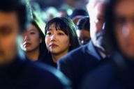 A blurry crowd of people with an Asian woman in focus at the center