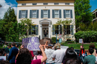 Students stand outside F Street House, the George Washington University president's residence, protesting and holding a sign that says "public safety equals no guns."