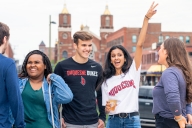 Students in Duquesne University T-shirts stand in a group on campus. 
