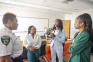 Three interns at the Baltimore Police Department talk to an officer.