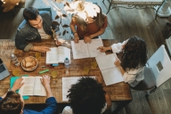 Overhead photo of group of diverse people around a table writing