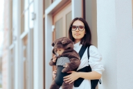 Woman holding baby in a front carrier stands before office door. The baby is, adorably, dressed as a bear.