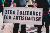 A person holds a sign saying "Zero tolerance for antisemitism"