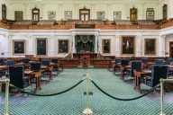 The Texas Senate chamber, with an aqua-blue rug and wooden desks and chair.