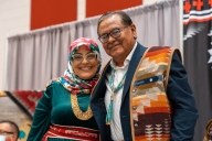 Navajo Technical University president Elmer Guy and Wafa Hozien, dean of Diné and graduate studies, stand together smiling at a campus event celebrating the new Ph.D. program. Both are wearing colorful Native prints. 