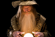 A wizard, dressed in a robe and pointy hat, stands with his hands hovering above a glowing crystal ball.
