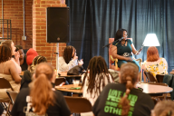 Students face President Mary Dana Hinton on stage in the Hollins University Rathskellar.