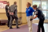 Police place two people in handcuffs in community college hallway.