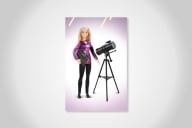 A blonde Barbie astrophysicist doll, dressed in a shiny purple shirt and black pants, standing next to a telescope.