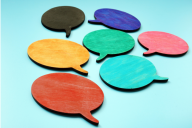 A cluster of seven brightly colored speech bubbles, in seven different colors, against a sky-blue background.