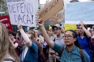 A group of young people hold up signs that read, "Defend DACA."