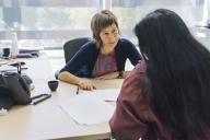 A college counselor meets with a young female student in her office.