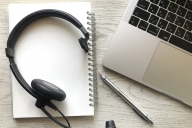 Photo of a computer, headset and pad with pen