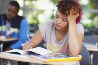 Young woman sits stressed and dejected at her desk in a classroom