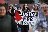 A group of protesters with a woman in the center holding a banner that says "Justice for Palestine"