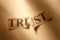 The word "TRUST," on a scrap of paper that has been torn in half.