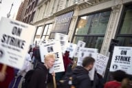 People demonstrating, holding signs saying "On Strike," with a Columbia College Chicago sign on the building behind them.
