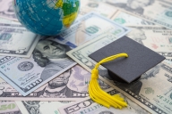 Mortar board sits on array of money bills alongside a globe