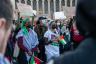 Students in masks and with Palestinian flags gather on an urban college campus