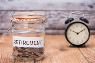 A jar of change, labeled with the word "Retirement," next to a clock.