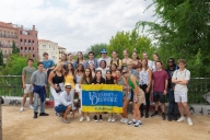 A group of students smile holding a University of Delaware flag while studying abroad.