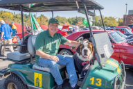 President Chuck Seifert sits in a green golf cart with school mascot, Baloo.