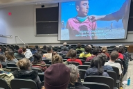 An auditorium of students watching a film