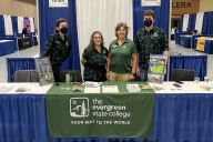 Four people stand behind a table with the words "the Evergreen State College" on a banner